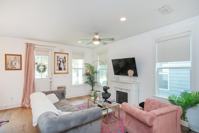 living room with ceiling fan, light wood-type flooring, and a premium fireplace