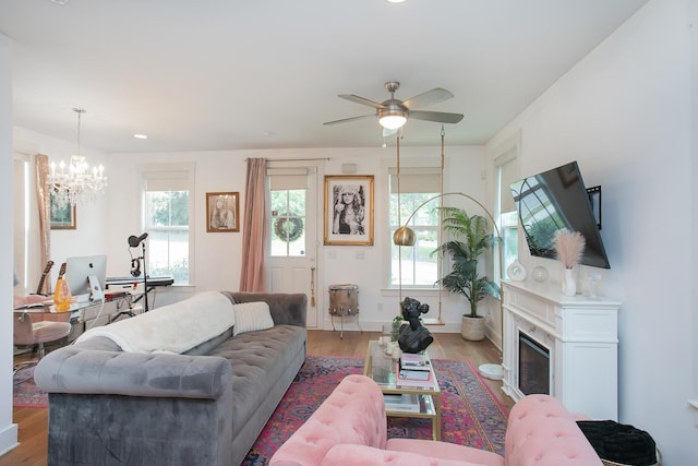 living room with a wealth of natural light, light hardwood / wood-style flooring, and ceiling fan with notable chandelier