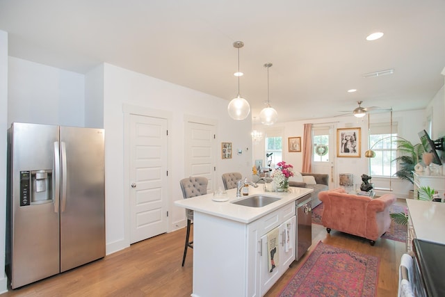 kitchen with white cabinets, sink, a breakfast bar area, decorative light fixtures, and stainless steel appliances