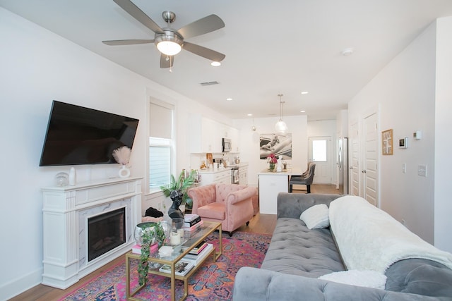 living room featuring a fireplace, hardwood / wood-style floors, and ceiling fan