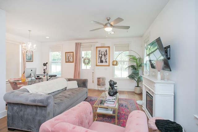 living room with light hardwood / wood-style flooring, ceiling fan with notable chandelier, and plenty of natural light