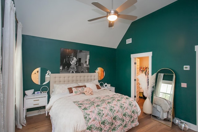 bedroom featuring a spacious closet, hardwood / wood-style floors, ceiling fan, and vaulted ceiling