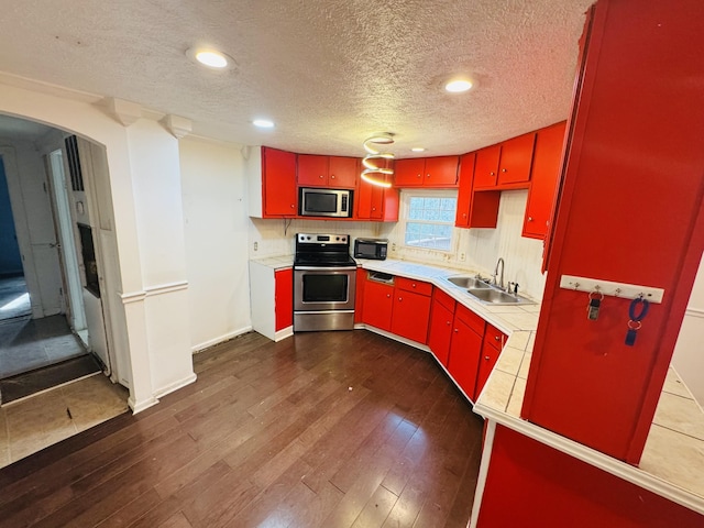 kitchen with a textured ceiling, sink, stainless steel appliances, and dark hardwood / wood-style floors