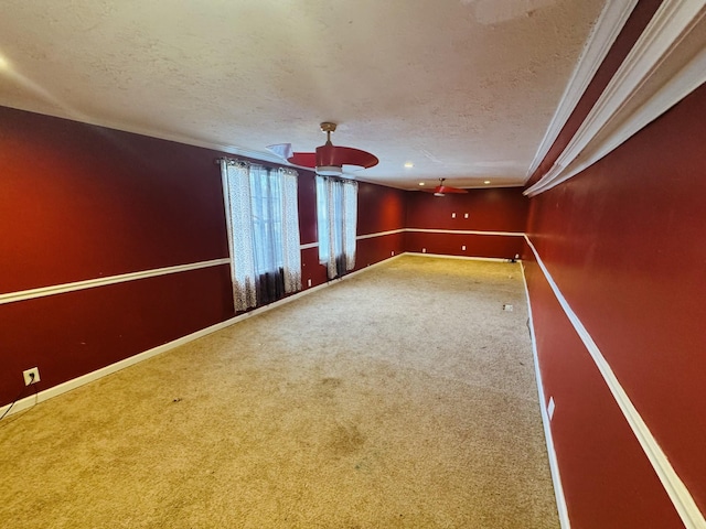 empty room with carpet, ceiling fan, crown molding, and a textured ceiling