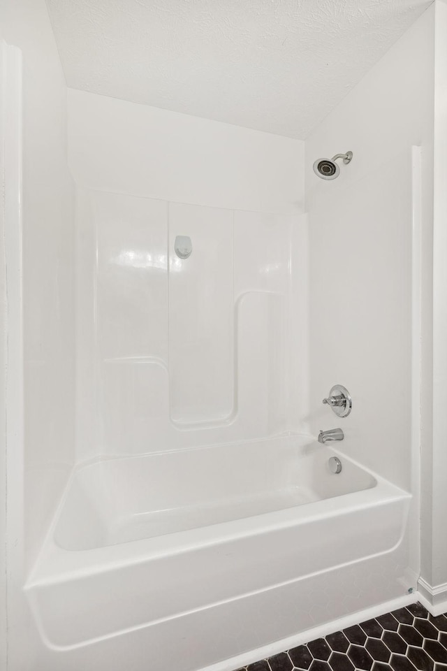 bathroom featuring a textured ceiling, tub / shower combination, and tile patterned flooring