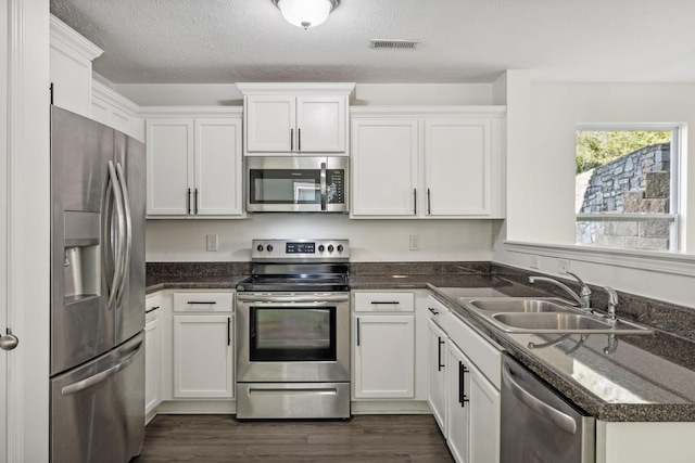 kitchen featuring dark hardwood / wood-style flooring, a textured ceiling, stainless steel appliances, sink, and white cabinetry