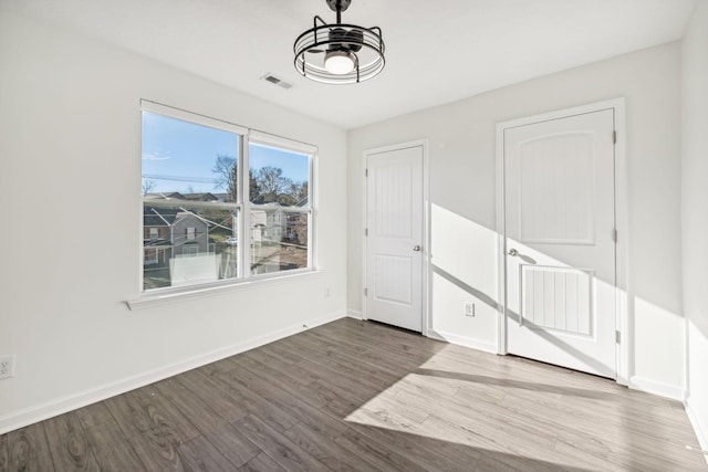 spare room featuring baseboards, visible vents, and wood finished floors