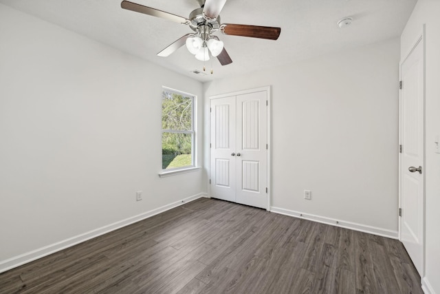 unfurnished bedroom featuring ceiling fan, dark wood-type flooring, and a closet