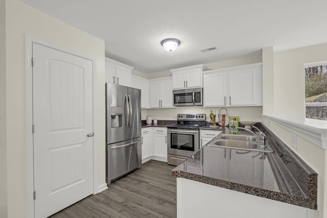 kitchen featuring visible vents, white cabinets, dark wood-style floors, appliances with stainless steel finishes, and a sink