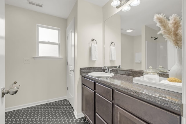 bathroom with tile patterned flooring, vanity, visible vents, baseboards, and a shower