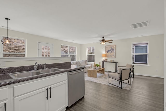 kitchen featuring visible vents, dishwasher, dark countertops, white cabinetry, and a sink