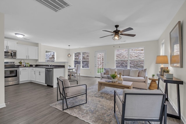 living room featuring baseboards, plenty of natural light, visible vents, and dark wood-style flooring