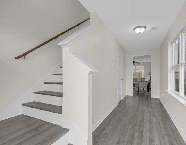 hallway with stairway, wood finished floors, and baseboards