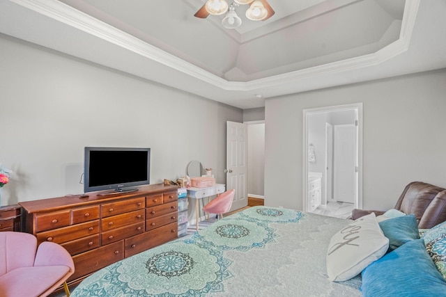 bedroom featuring ceiling fan, ensuite bathroom, ornamental molding, and a tray ceiling