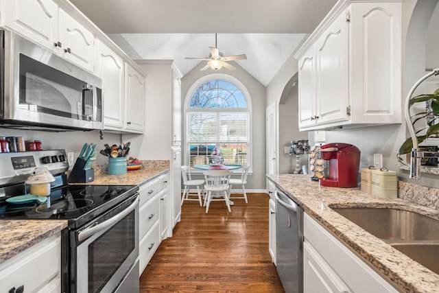 kitchen with appliances with stainless steel finishes, dark wood finished floors, white cabinets, and vaulted ceiling