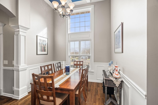 dining area featuring decorative columns, a notable chandelier, crown molding, and dark hardwood / wood-style flooring