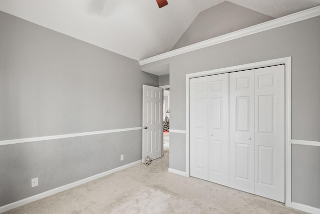 unfurnished bedroom featuring a closet, light colored carpet, vaulted ceiling, and baseboards