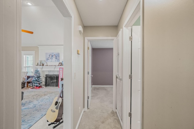 hall featuring light colored carpet and baseboards