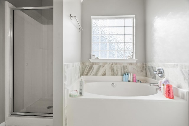 bathroom featuring a garden tub and a shower stall