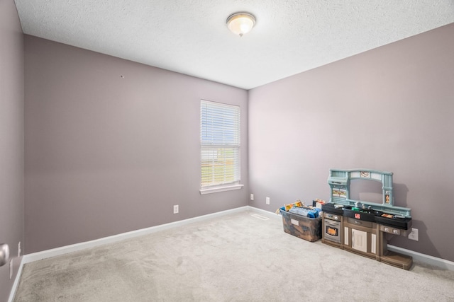 playroom featuring a textured ceiling, carpet floors, and baseboards