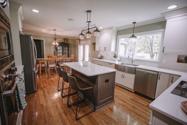 kitchen featuring a breakfast bar, light hardwood / wood-style flooring, appliances with stainless steel finishes, a kitchen island, and white cabinetry