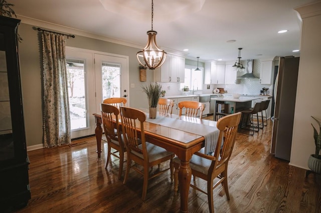 dining space featuring hardwood / wood-style flooring, a notable chandelier, ornamental molding, and sink