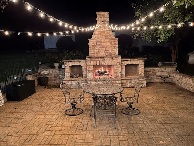 patio at night featuring an outdoor stone fireplace