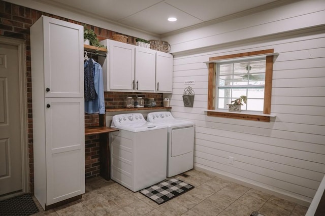 laundry room with cabinets, washing machine and dryer, ornamental molding, and wooden walls