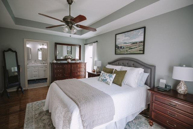 bedroom featuring ensuite bathroom, dark hardwood / wood-style floors, a raised ceiling, and ceiling fan