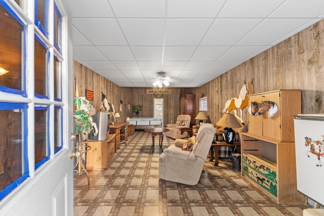 living room featuring a paneled ceiling and wood walls