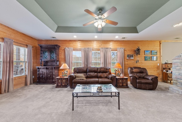 living room with light colored carpet, a tray ceiling, and a healthy amount of sunlight