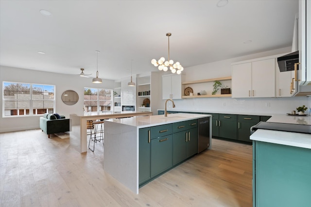 kitchen featuring a kitchen island with sink, light countertops, hanging light fixtures, and white cabinetry