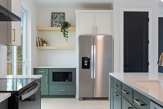 kitchen with black microwave, white cabinets, wall chimney range hood, stainless steel refrigerator with ice dispenser, and open shelves