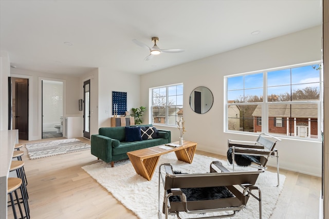 living room featuring light wood-type flooring, ceiling fan, and baseboards