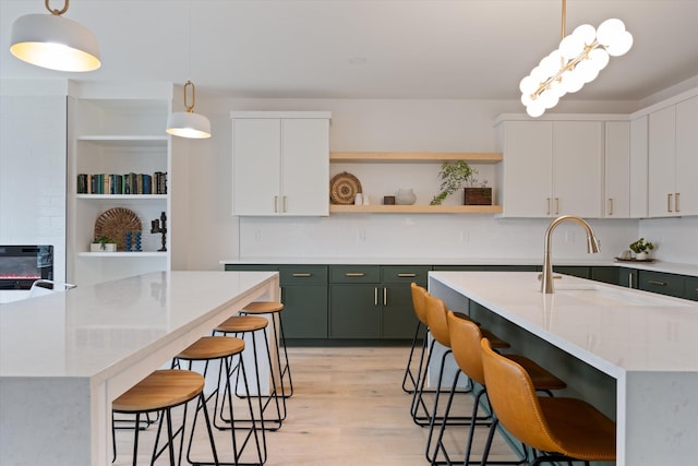 kitchen with a kitchen breakfast bar, hanging light fixtures, an island with sink, and open shelves