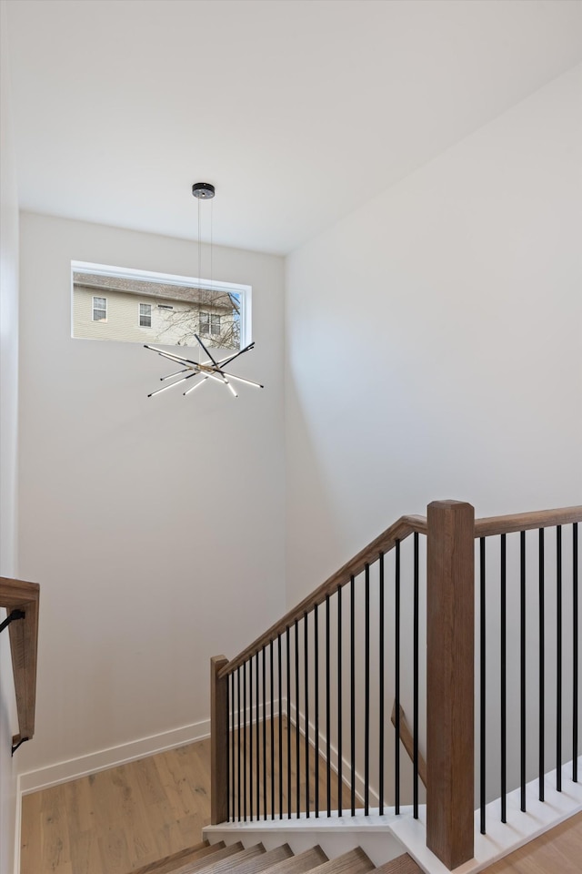 stairs featuring baseboards, a chandelier, and wood finished floors