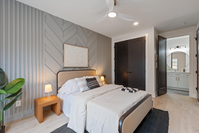 bedroom featuring ensuite bath, wallpapered walls, light wood-style flooring, and baseboards