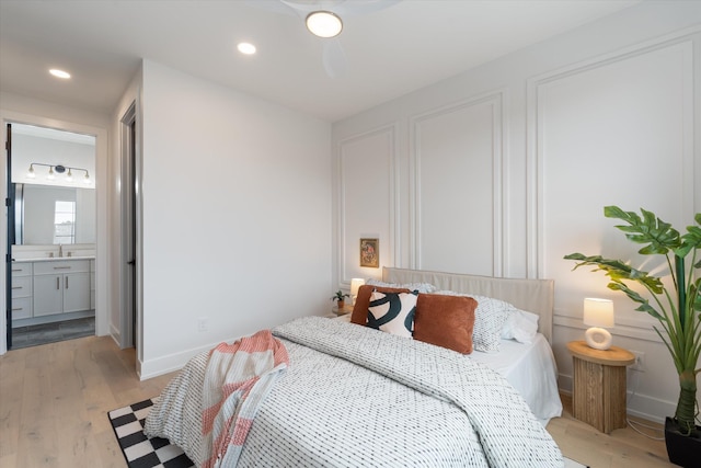 bedroom with connected bathroom, recessed lighting, a sink, baseboards, and light wood-type flooring