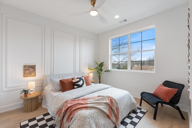 bedroom featuring ceiling fan, light wood-style flooring, visible vents, and baseboards