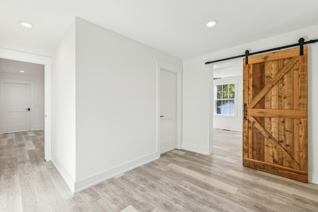 spare room featuring a barn door and light hardwood / wood-style floors