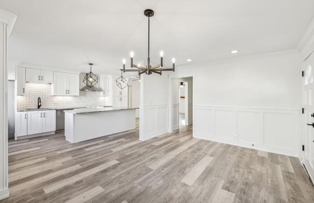 kitchen with pendant lighting, a chandelier, white cabinets, a center island, and light hardwood / wood-style floors