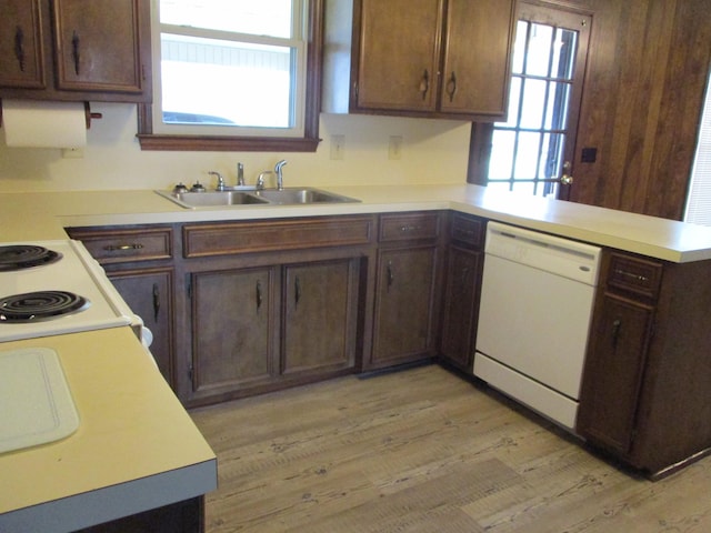 kitchen with kitchen peninsula, white appliances, dark brown cabinetry, sink, and light hardwood / wood-style flooring