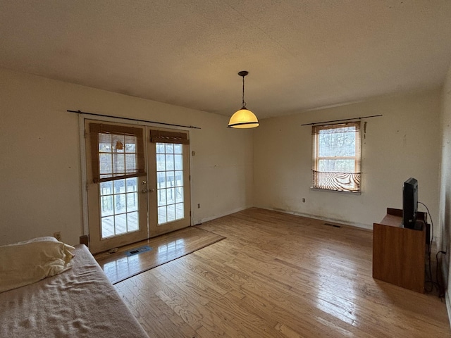 dining space featuring light hardwood / wood-style floors, french doors, and a textured ceiling