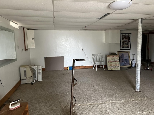 basement featuring a paneled ceiling and electric panel