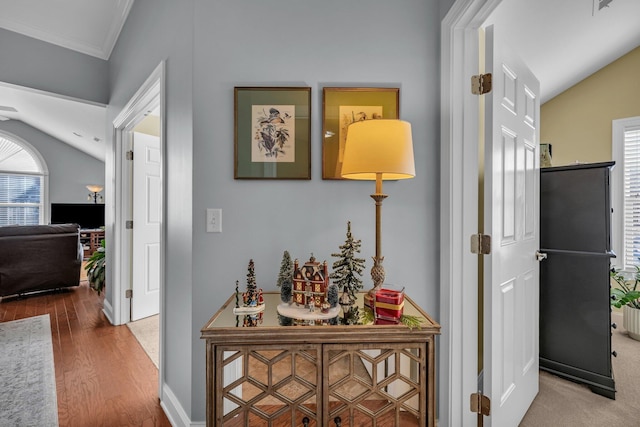 hall featuring hardwood / wood-style flooring, lofted ceiling, and ornamental molding