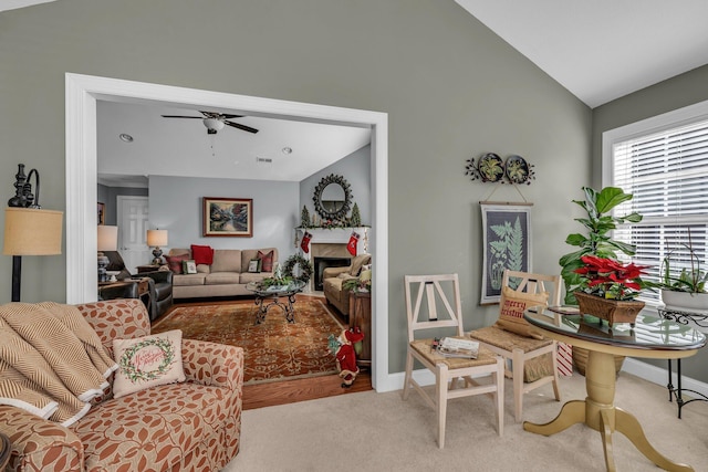 carpeted living room with ceiling fan and vaulted ceiling