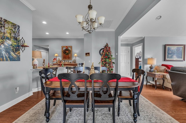 dining room with a chandelier, hardwood / wood-style flooring, and crown molding