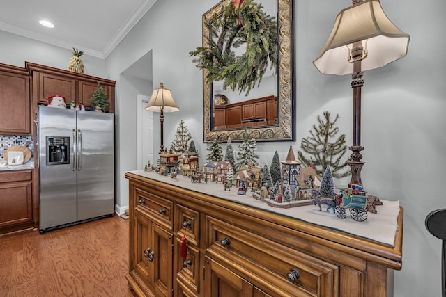 kitchen with backsplash, stainless steel fridge, light hardwood / wood-style floors, and crown molding