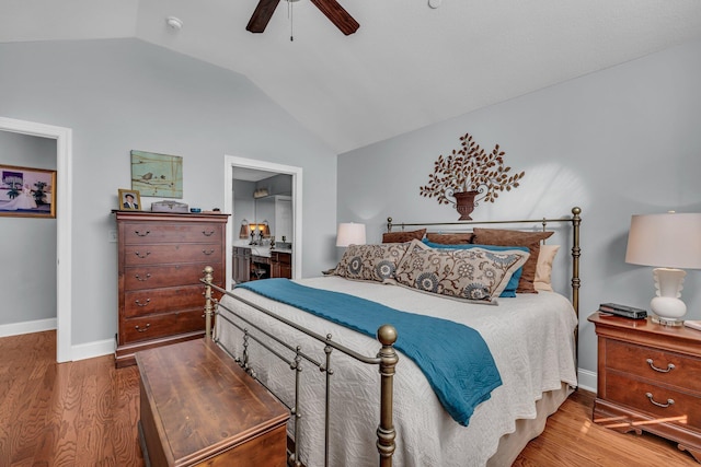 bedroom featuring wood-type flooring, connected bathroom, vaulted ceiling, and ceiling fan