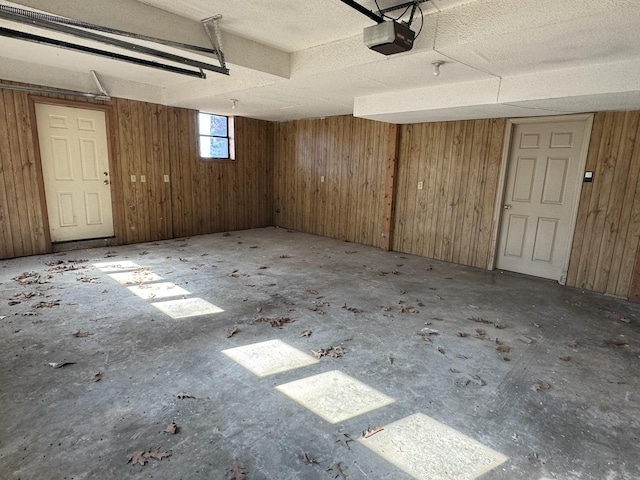 garage with a garage door opener and wood walls